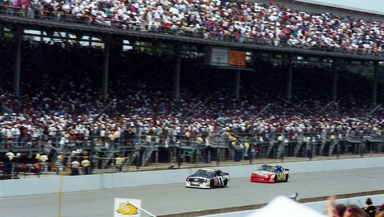 Jeff Gordon's rainbow No. 24 racing Rick Mast in front of the Indianapolis grandstands
