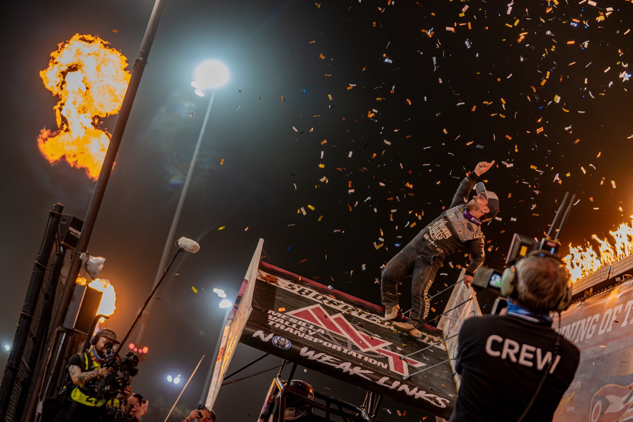 Winner celebrating on the car in victory lane with flames and confetti